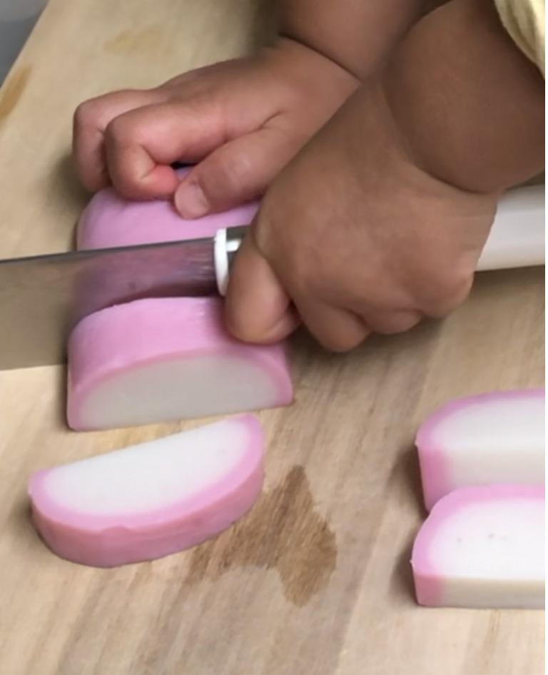 ３歳の娘が包丁でかまぼこを切っています
